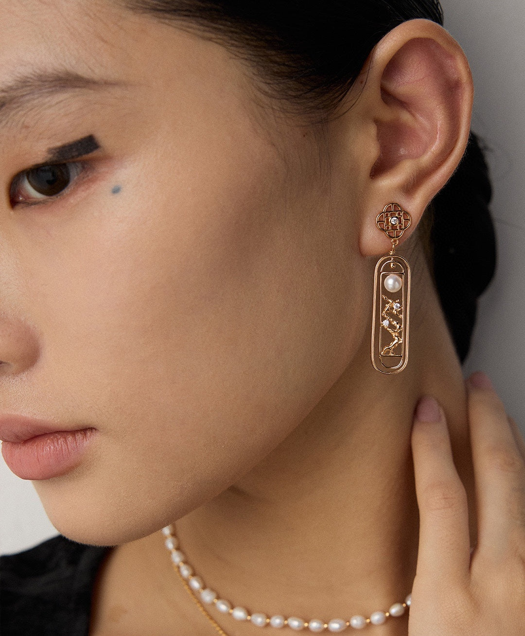 Long freshwater pearl window drop earring worn beside a black square neckline