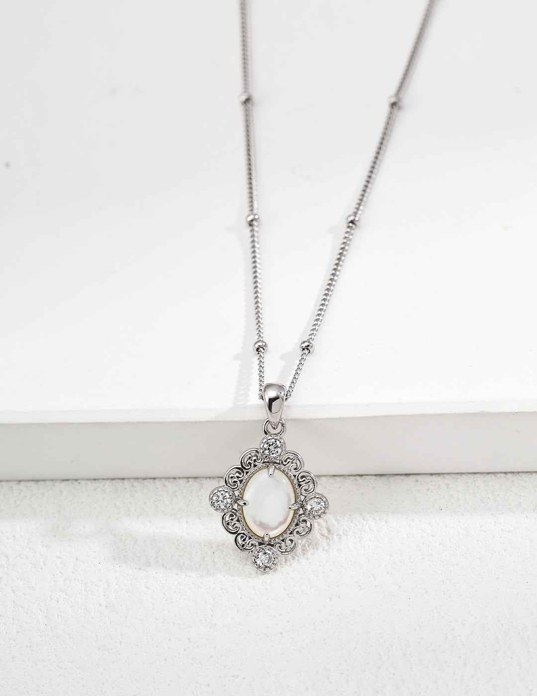 Close-up of sterling silver pendant showing amethyst stone in ornate frame with CZ accents