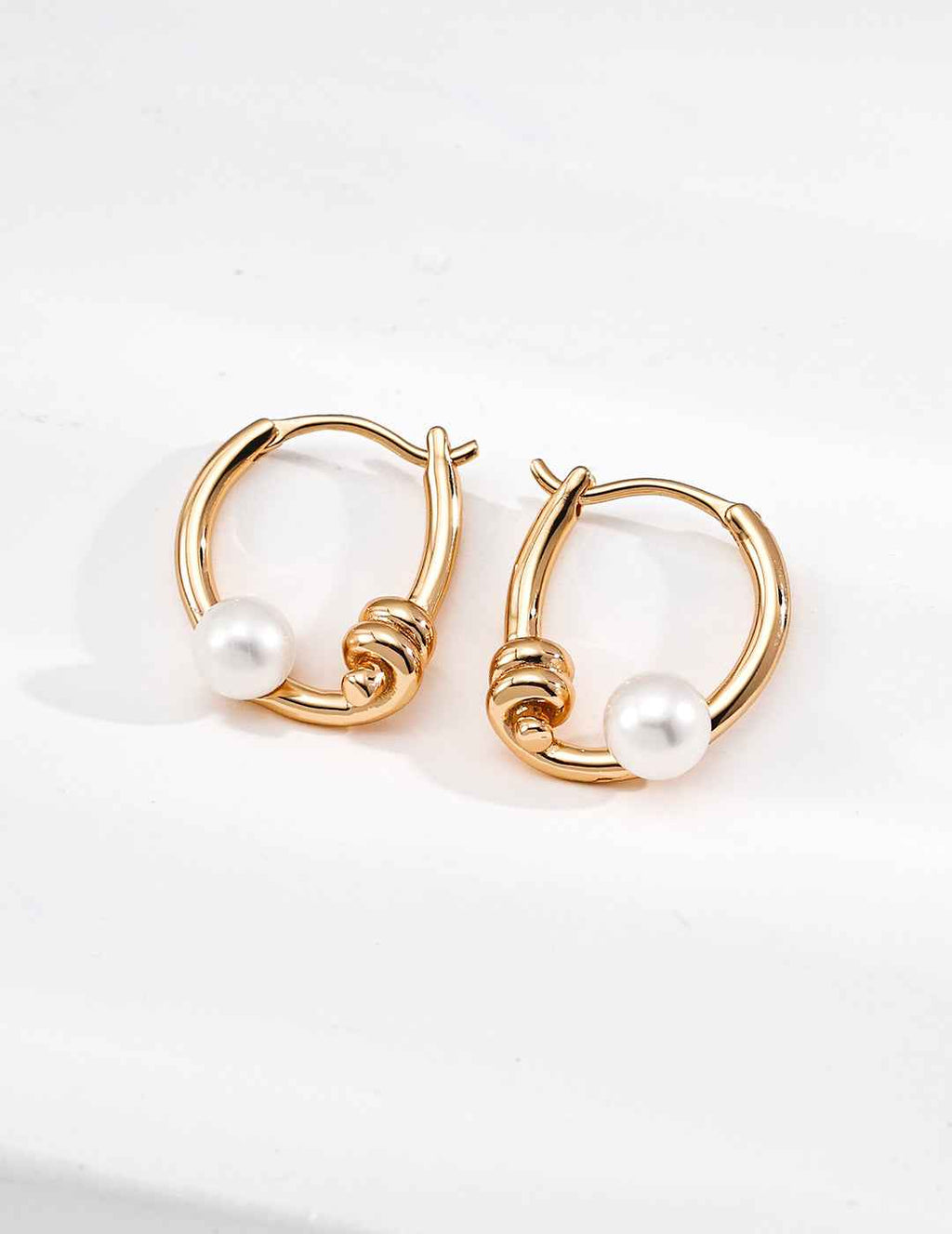 Pair of 925 sterling silver curved line pearl hoop earrings worn on ears
