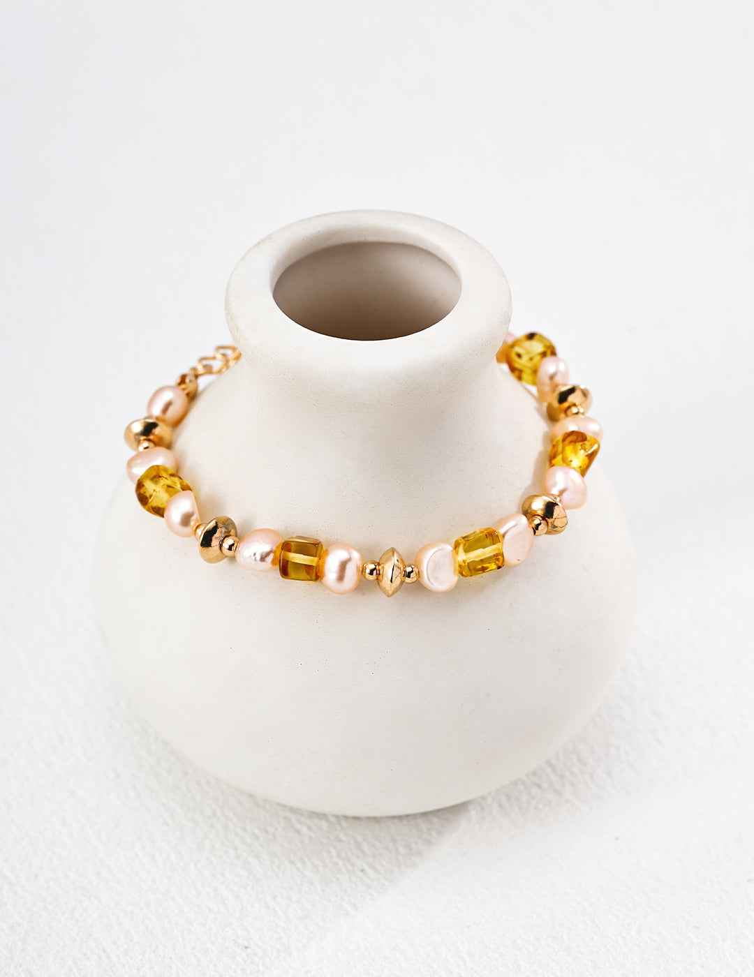 Full view of beaded bracelet with alternating amber and pearl beads, gold-tone clasp