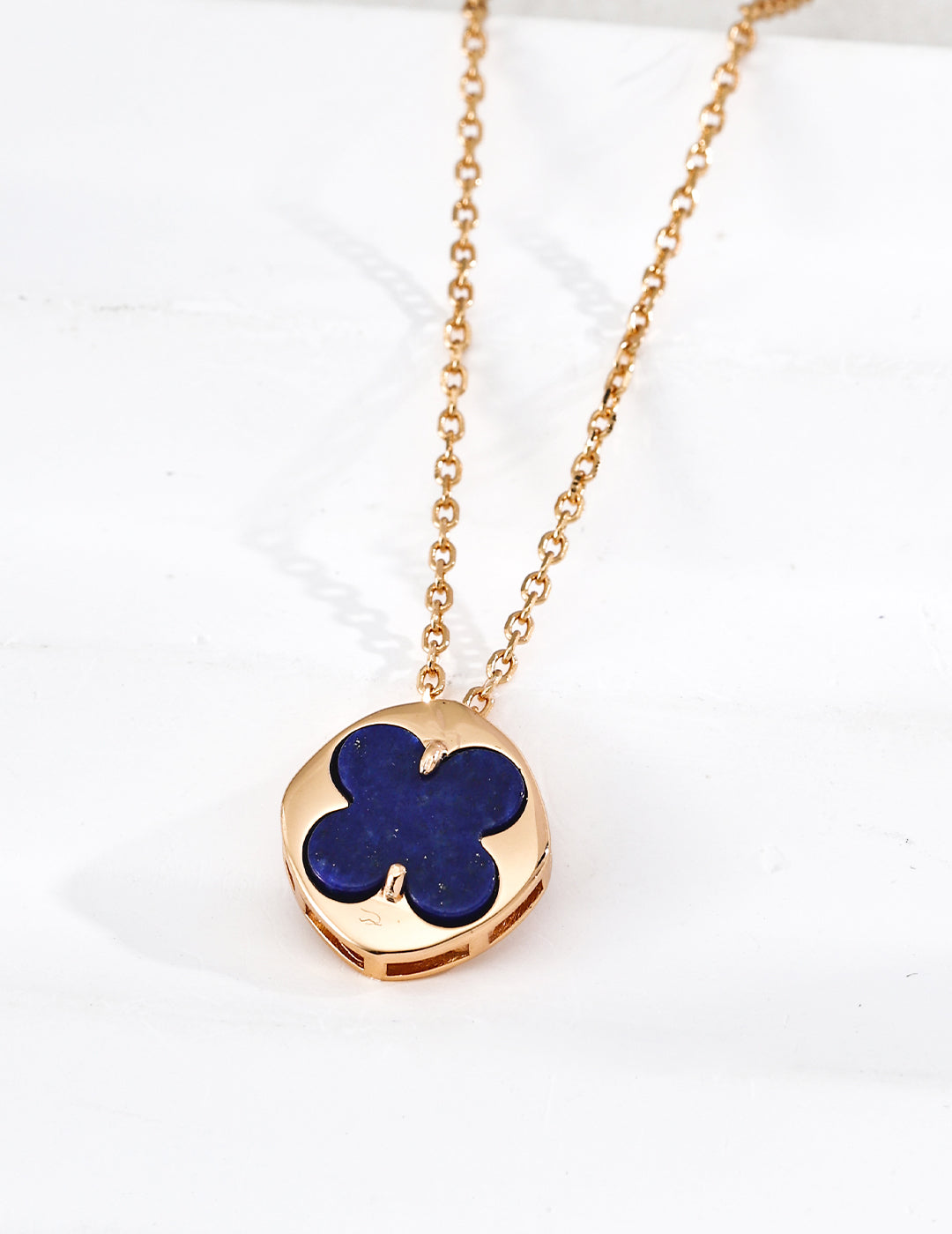 Close-up of sterling silver clover pendant showing polished stone inlay and gold-tone frame detail