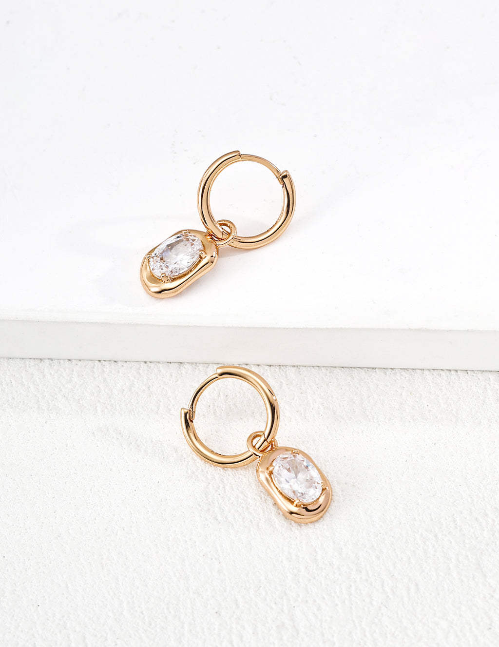 Close-up of sterling silver drop hoop earring showing CZ detail and metal frame