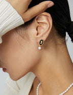 Close-up of black enamel oval earring showing detailed gold-tone edging