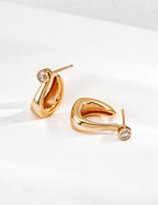 Close-up of sterling silver curved CZ hoop earring showing flowing silhouette and stone detail