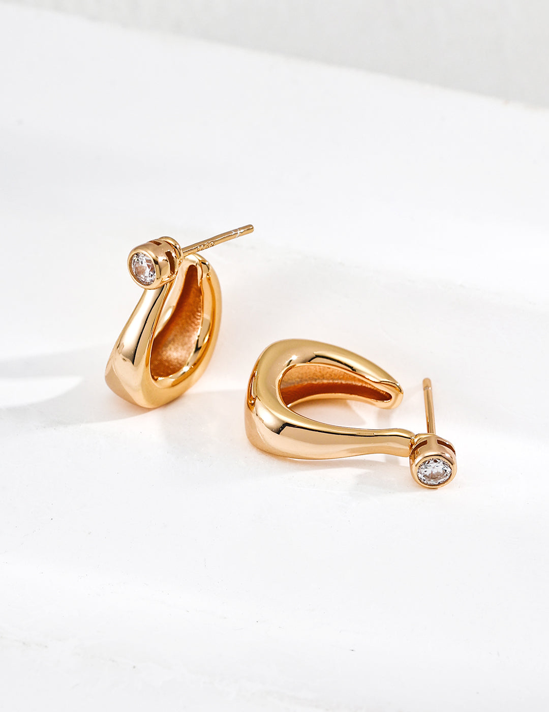 Close-up of sterling silver curved CZ hoop earring showing flowing silhouette and stone detail