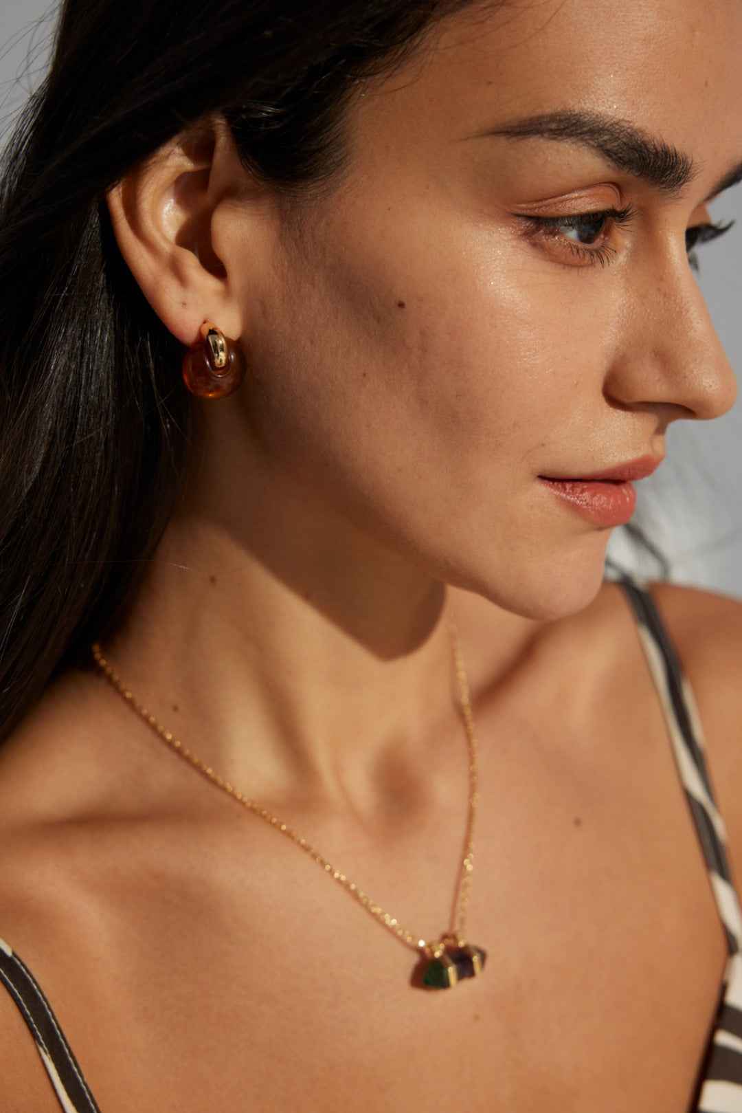 Front view of 925 sterling silver amber-toned resin hoop earrings, rounded shape