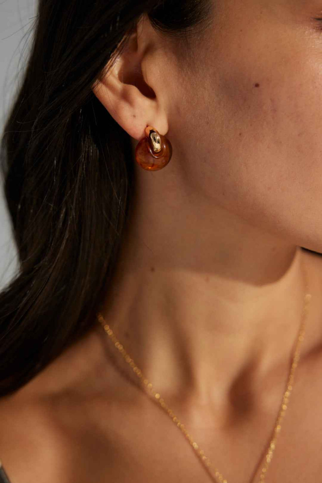 Close-up of sterling silver resin hoop earrings showing translucent warm-toned surface