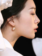 Close-up of sterling silver round pearl drop earring showing smooth surface and gold-tone setting