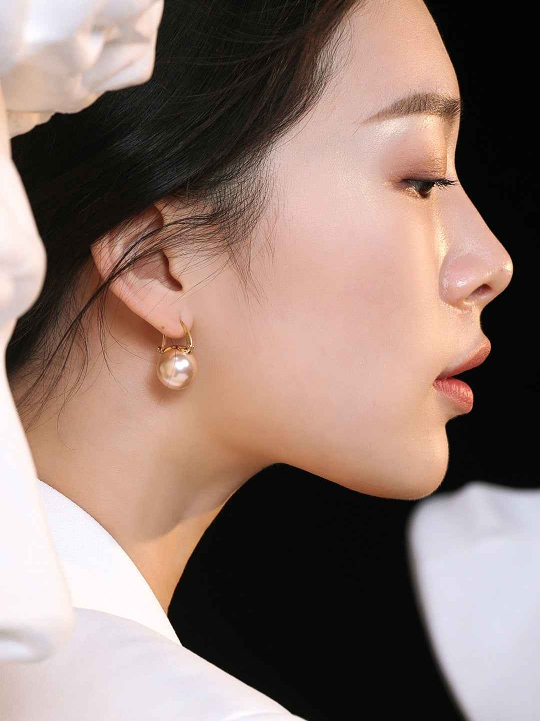 Close-up of sterling silver round pearl drop earring showing smooth surface and gold-tone setting