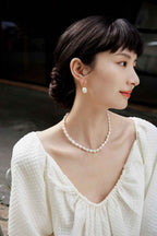 Close-up of natural baroque pearl drop earring showing irregular surface and gold-tone setting