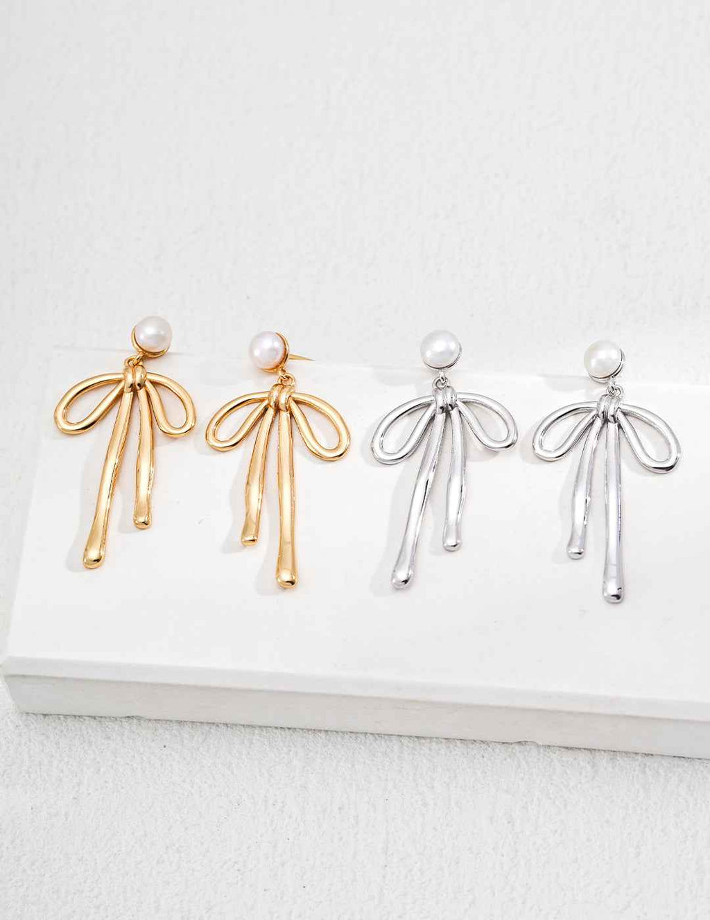 925 sterling silver bow drop earrings with pearl accent, worn on ear