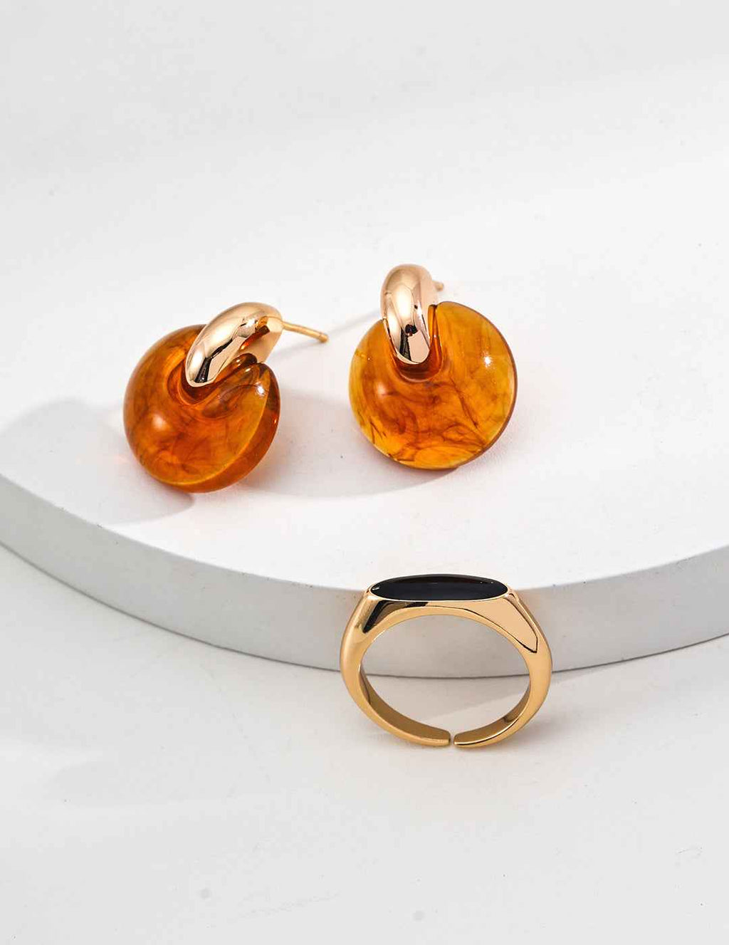 Pair of sterling silver amber-inspired resin hoop earrings displayed flat