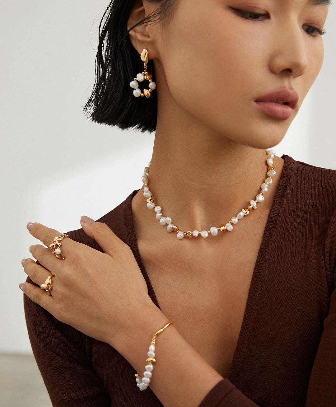 Freshwater pearls repeated at the neck and wrist with warm gold-tone details