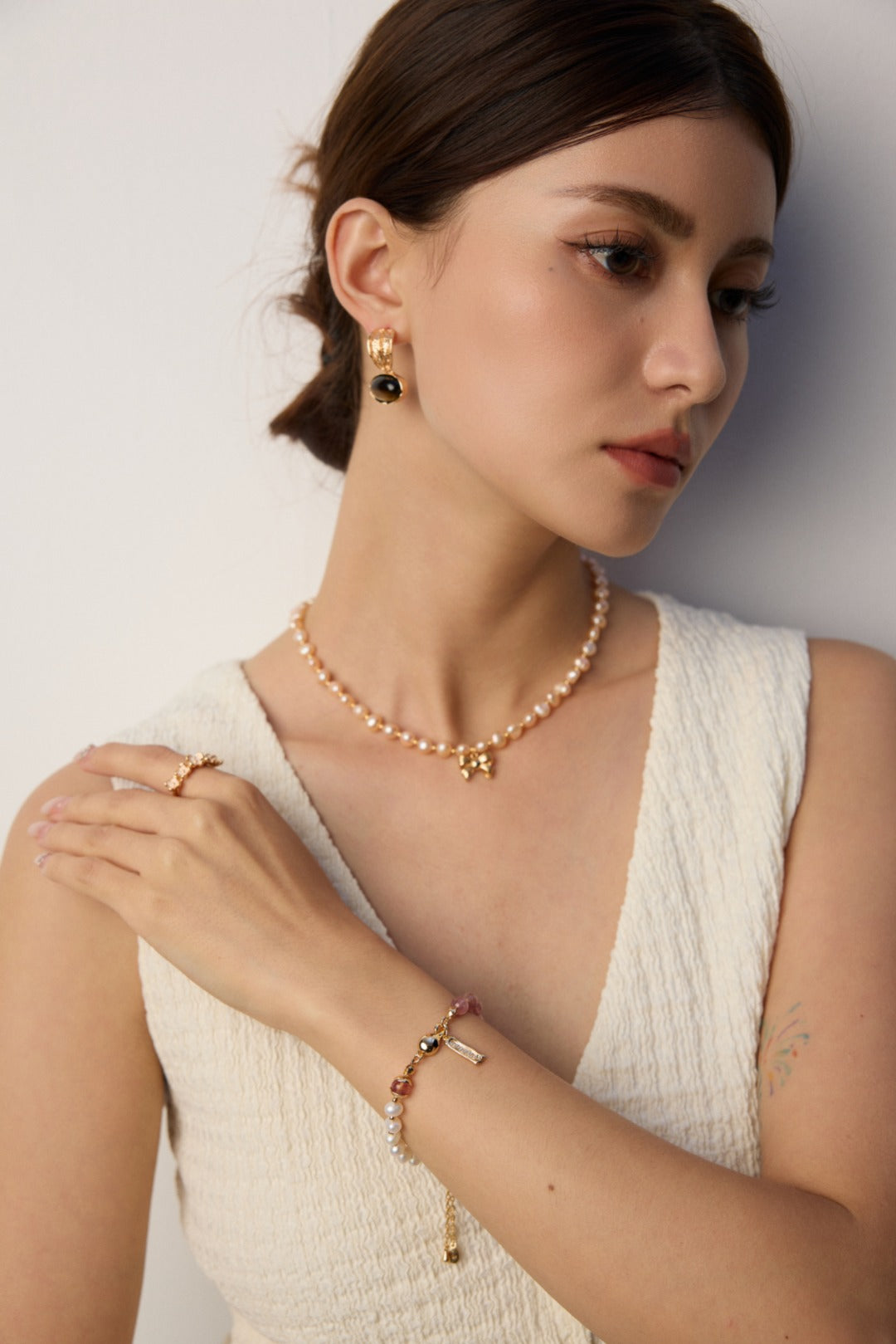 Black agate and tiger’s eye earring beside a clear ear and pale textured neckline