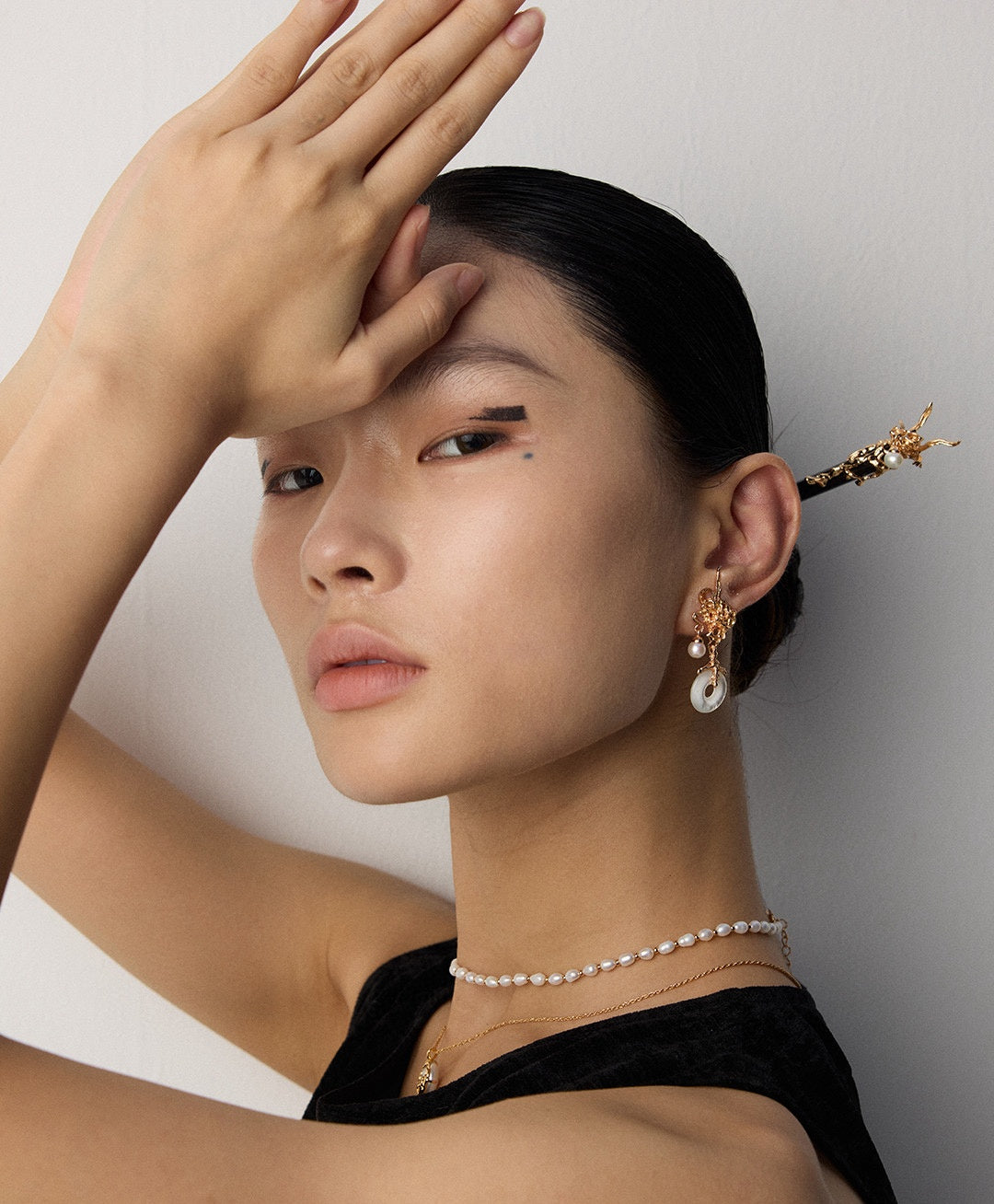 Pearl necklace, drop earrings and decorative hair stick styled with a black top