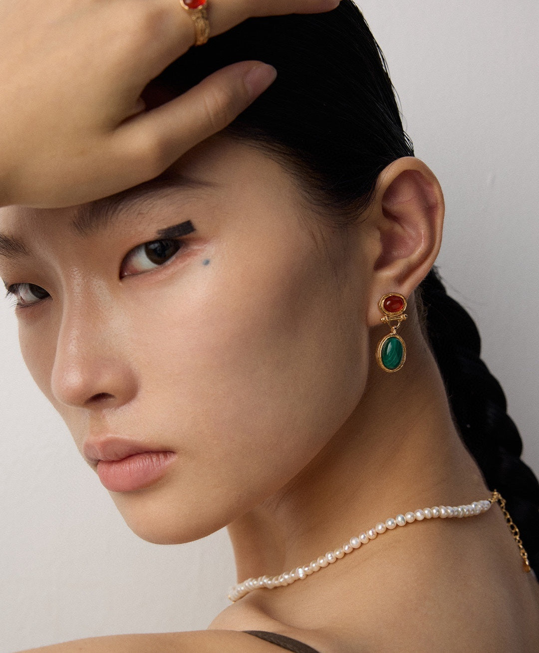 Green malachite and red agate earrings styled beside a matching colour accent